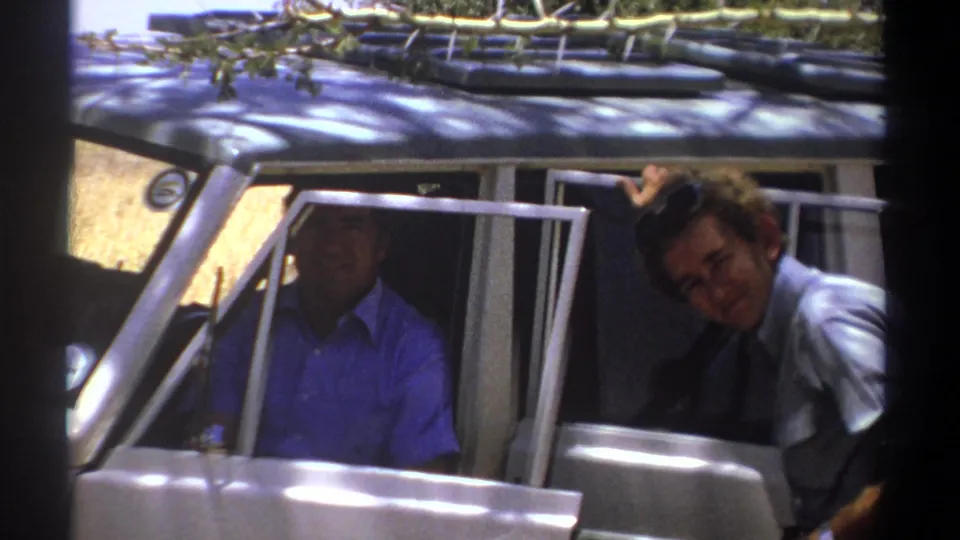A darker exposed frame shows a man seated inside the white vehicle while his companion remains near the open doorway.