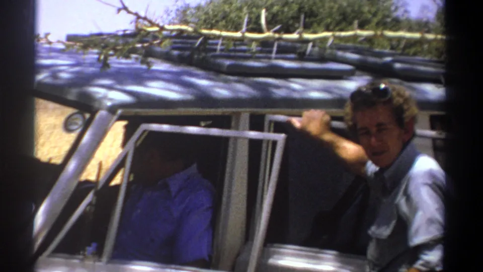 Near the end of the Kenya 1969 clip, one man leans from the white vehicle toward the camera while another remains inside.