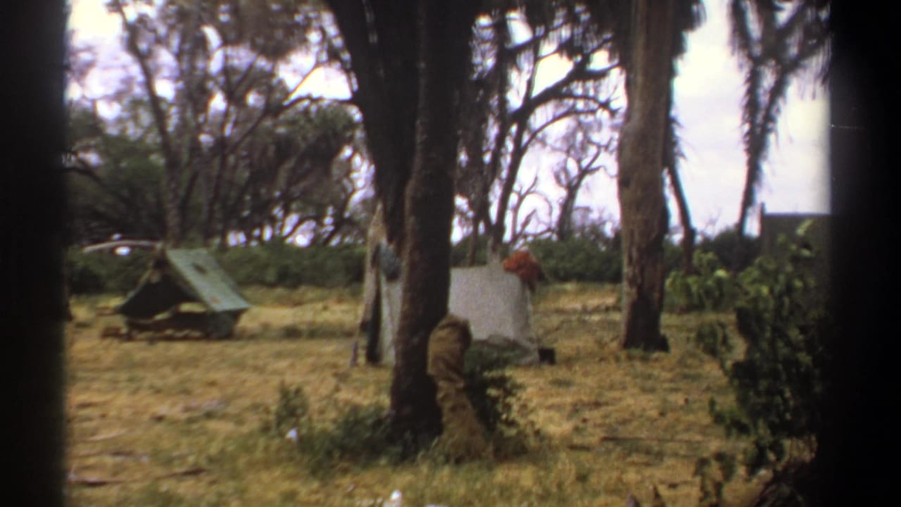 1969 Kenya 8mm frame showing a green tent and a light tent set among trees in a dry campsite clearing.