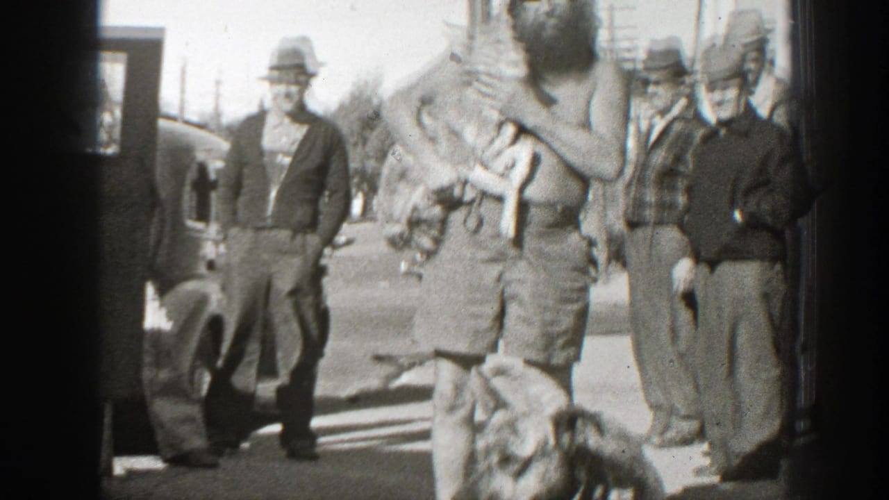 In 1939 California home-movie footage, a bearded shirtless man holds two turtles as adult men in hats stand around him outdoors.
