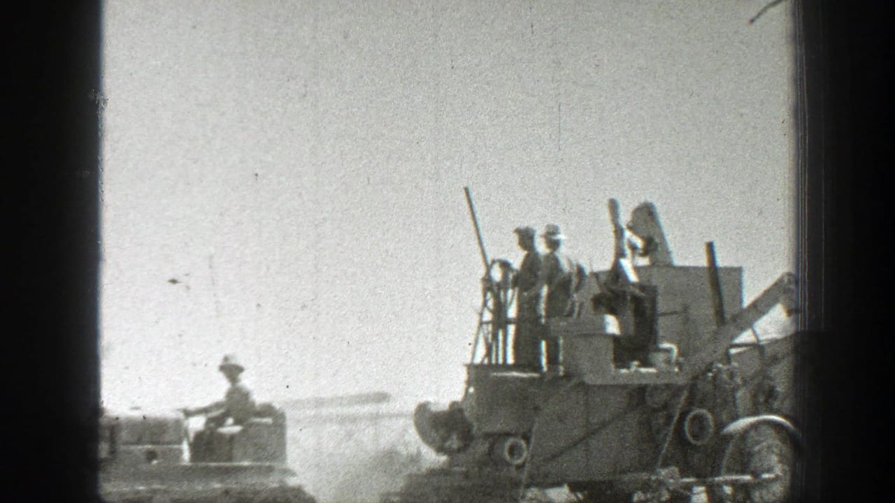 Workers on a combine beside a tractor in a dusty field.