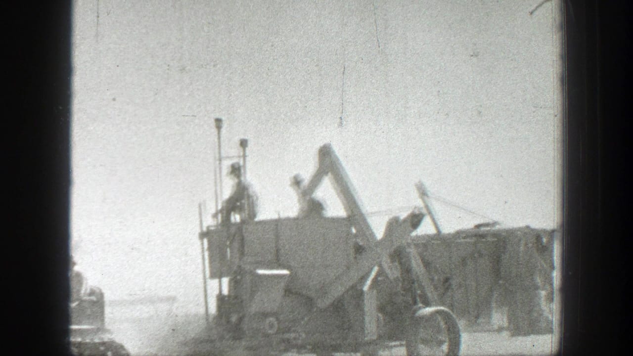 Soldiers stand on and around a large military vehicle in a dusty open road setting.