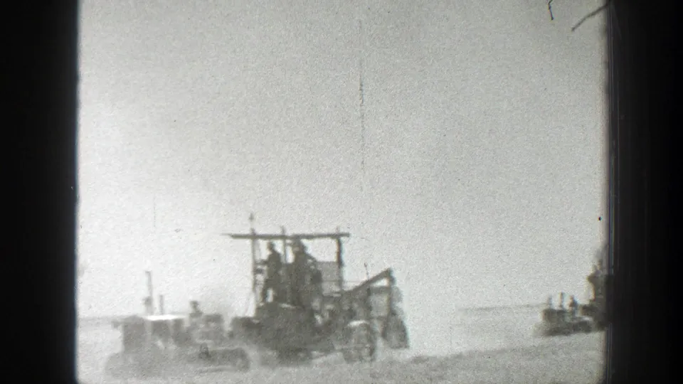Distance view of old farm machinery and operators in a dusty 1939 California agricultural setting.