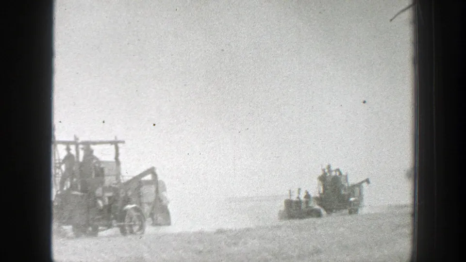 A 1939 California 8mm frame shows workers riding open harvesting machinery across a bright, dusty agricultural field.
