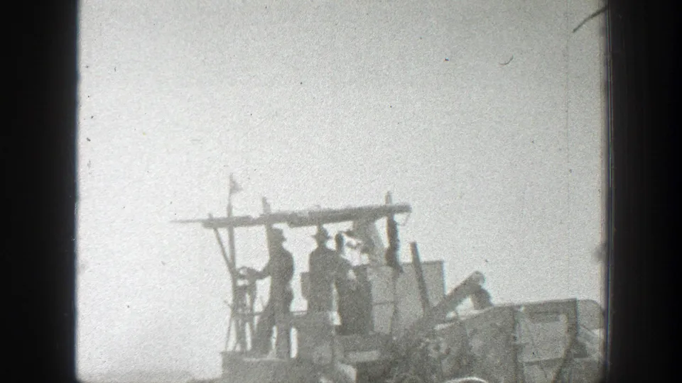 Closer 1939 California frame with several workers standing on an open harvester structure amid dusty field conditions.