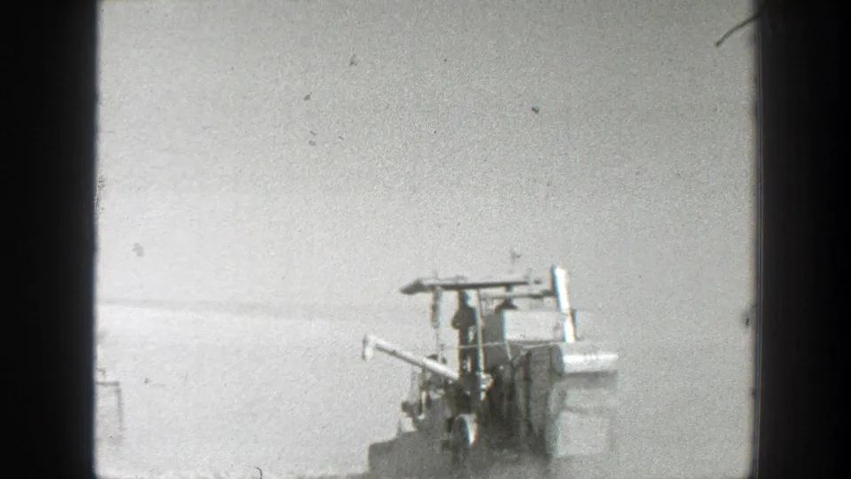 Partial 1939 California 8mm view of a harvester structure and operator area against a bright field.