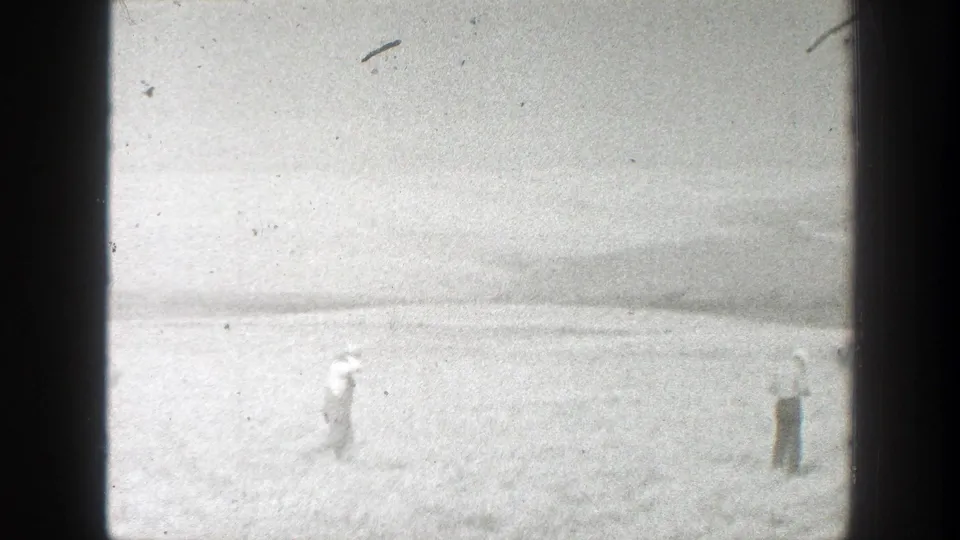 1939 California rural field view with distant workers spaced across the landscape in grainy black-and-white 8mm footage.