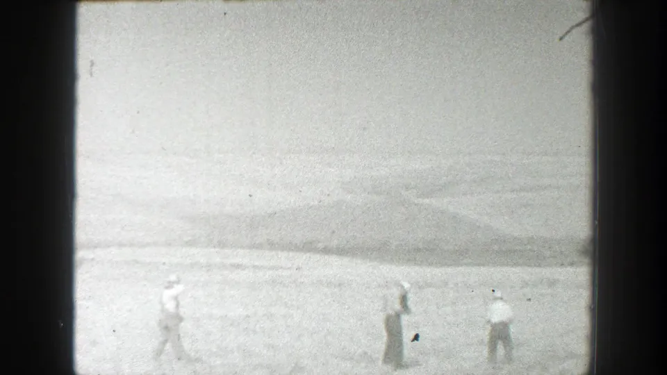 1939 California home-movie frame showing workers dispersed in a broad rural field, with visible grain and frame border.