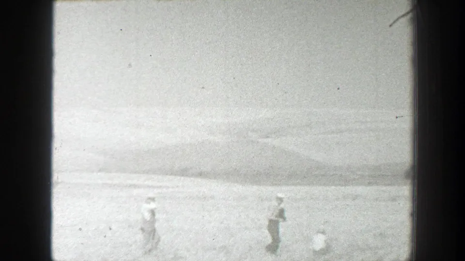 1939 California field scene with several distant workers visible across the lower frame in soft 8mm black-and-white footage.