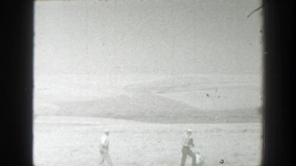 Two distant figures cross an open California field in 1939 home-movie footage, with soft focus and dark 8mm frame borders.