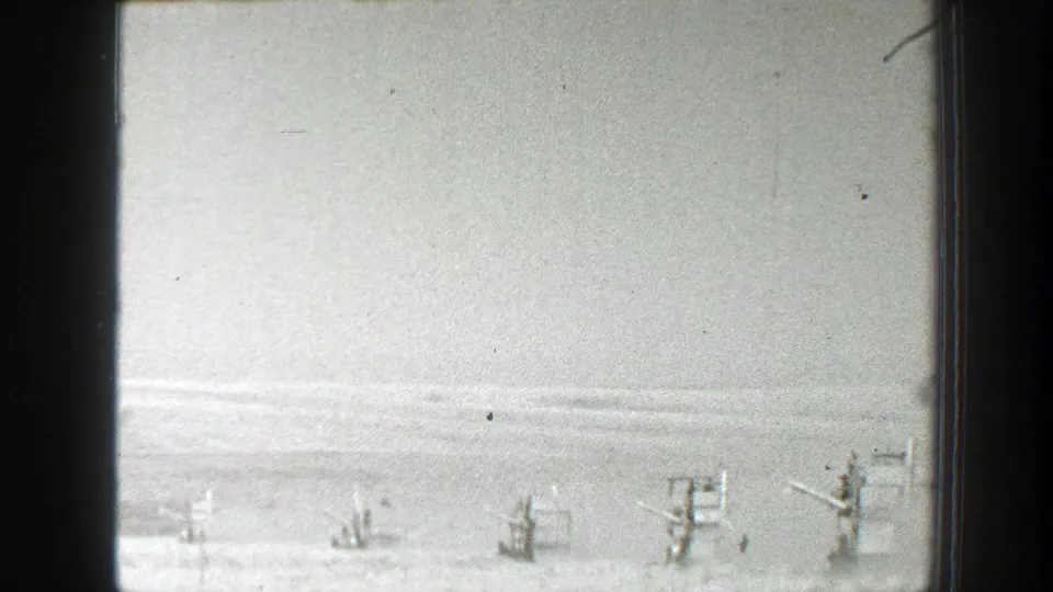 1939 California home-movie frame showing small farm machines spread across a flat field beneath a pale sky.