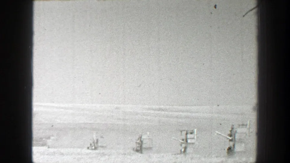Distant agricultural equipment appears along the horizon of a flat California field in grainy 1939 8mm footage.