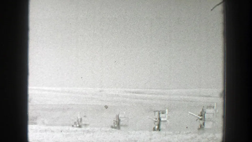 Late frame of the 1939 California field scene, with several small machines visible near the horizon through 8mm film texture.