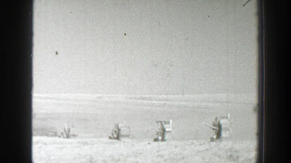 A 1939 California home-movie frame shows soldiers at a distance beside small wooden positions in a snowy open field.