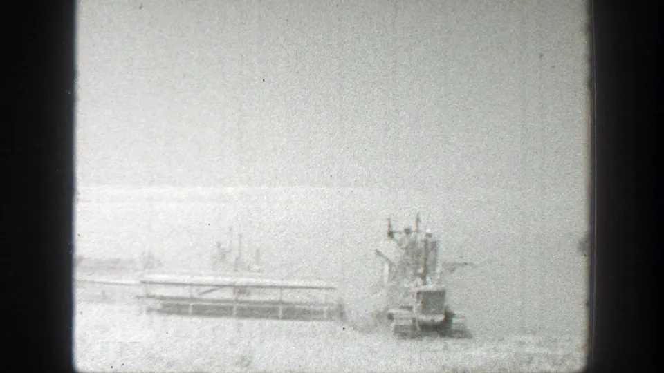 A tractor-mounted harvesting rig appears in a bright California field, with the pale machinery shape visible against the horizon.