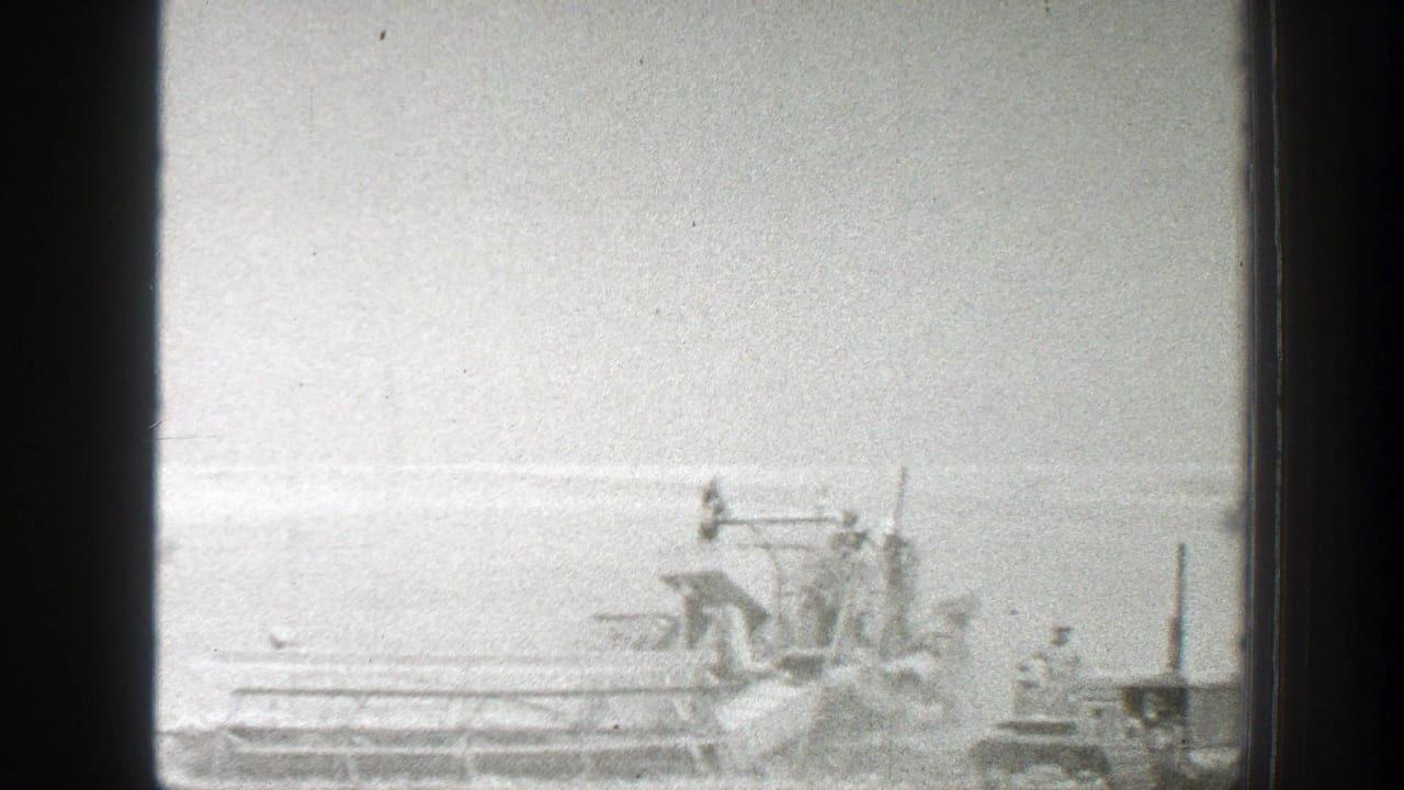 1939 California 8mm frame showing harvester machines spread across a bright rural field under a pale sky.