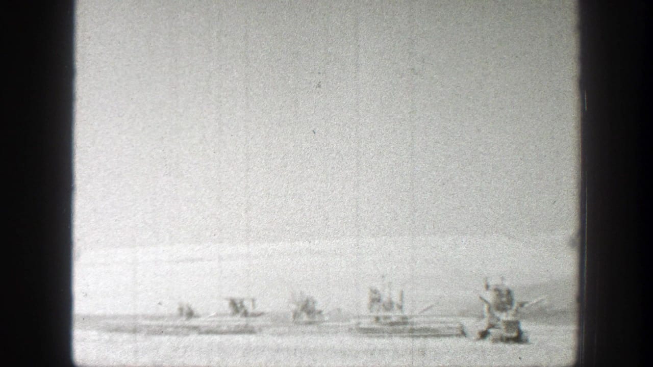 Distant farm machines work across a bright open field.