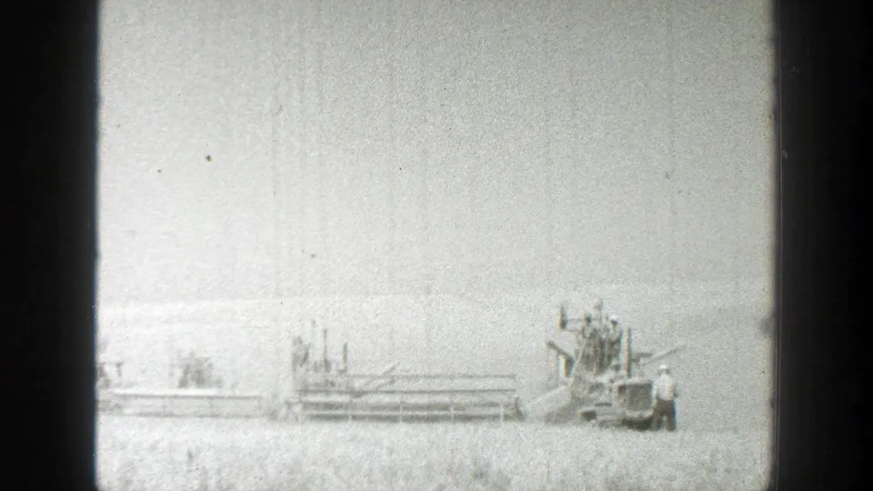 1939 California frame showing large farm equipment at right, with a small standing person visible nearby in the field.