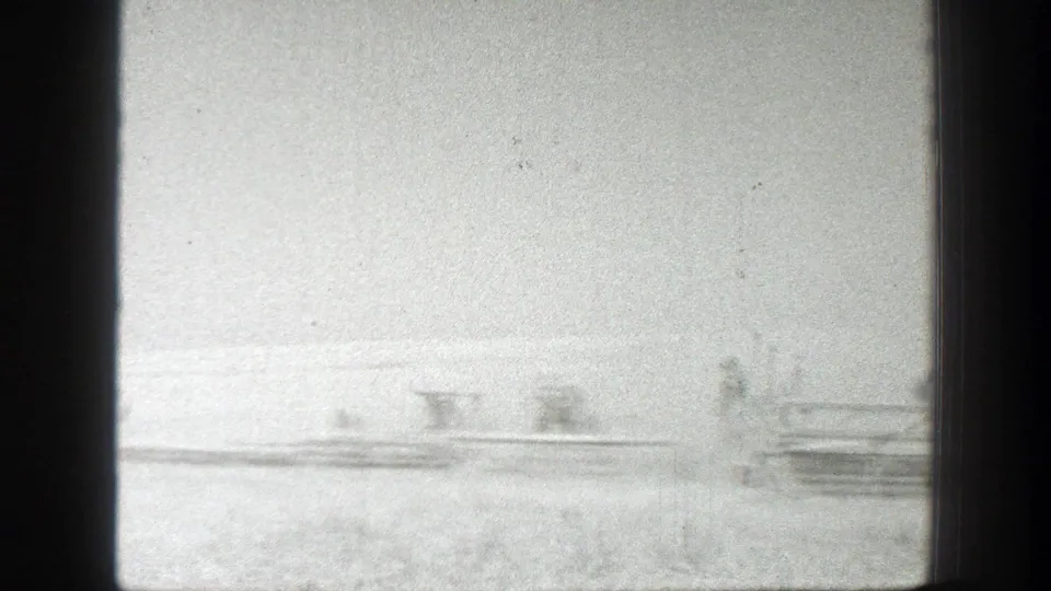 Overexposed 8mm view of California harvest machinery and distant workers in a wheat field, circa 1939.