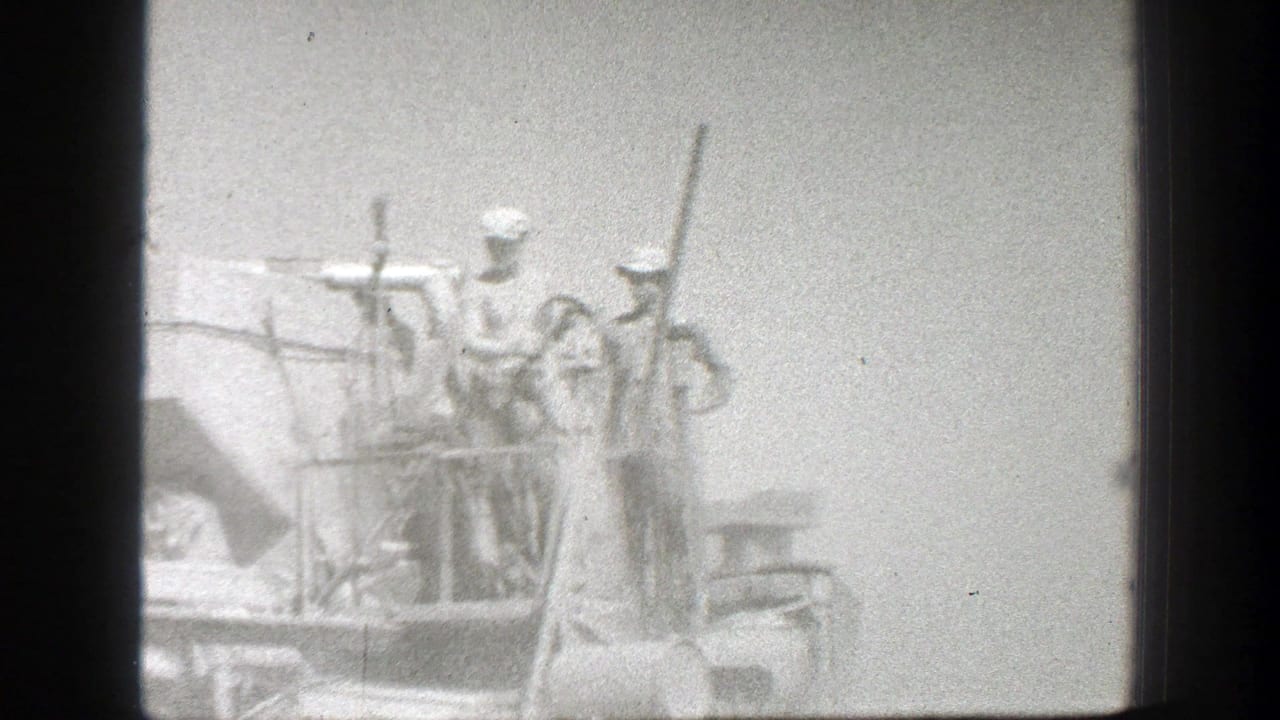 Workers stand on top of heavy machinery in a hazy black-and-white frame.