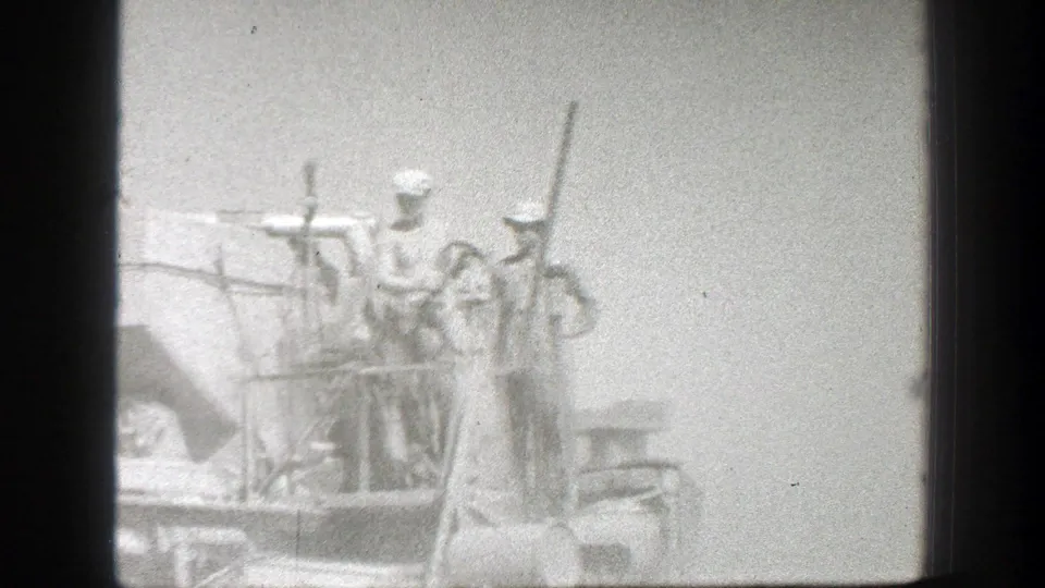 California 1939 home-movie frame showing men in hats standing on elevated heavy equipment with railings and exposed controls.