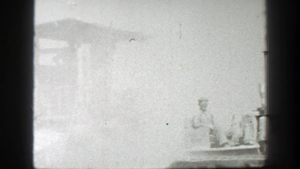 Soft black-and-white California 1939 frame with a worker and machinery barely visible through haze at the right side.