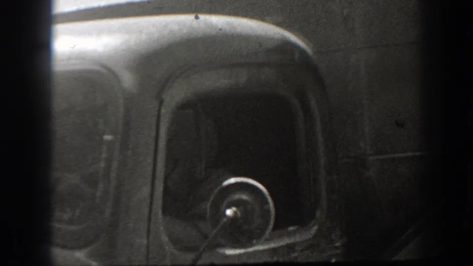 A close, darkly exposed view shows the rounded cab, window, and side mirror of a vintage truck in 1939 California footage.