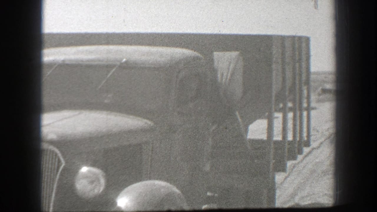 1939 California home-movie frame showing the front of a vintage truck stopped beside a roadside structure or barrier.
