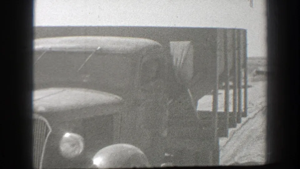 1939 California home-movie frame showing the front of a vintage truck stopped beside a roadside structure or barrier.