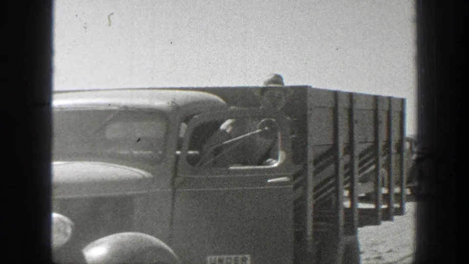 Close 1939 California view of a period cargo truck passing near the camera on a dusty road.