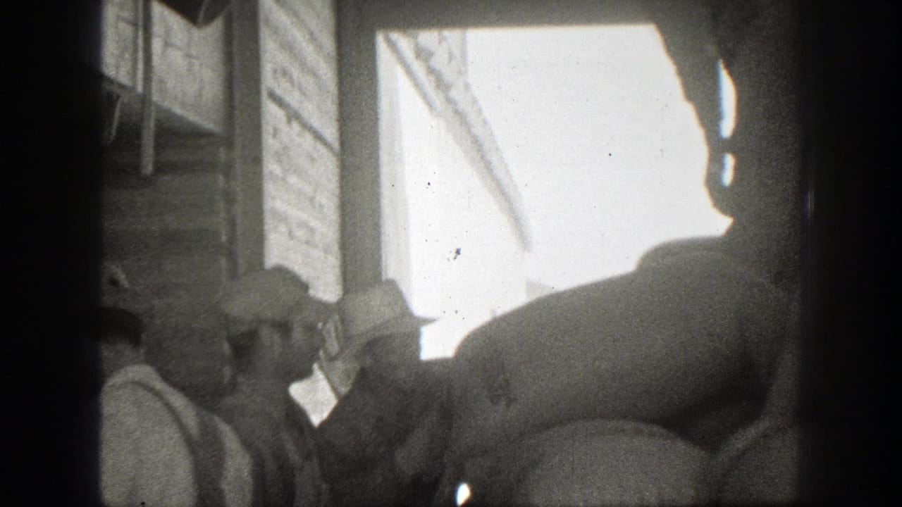 1939 California 8mm frame showing men in period workwear handling large sacks near a loading dock or doorway.