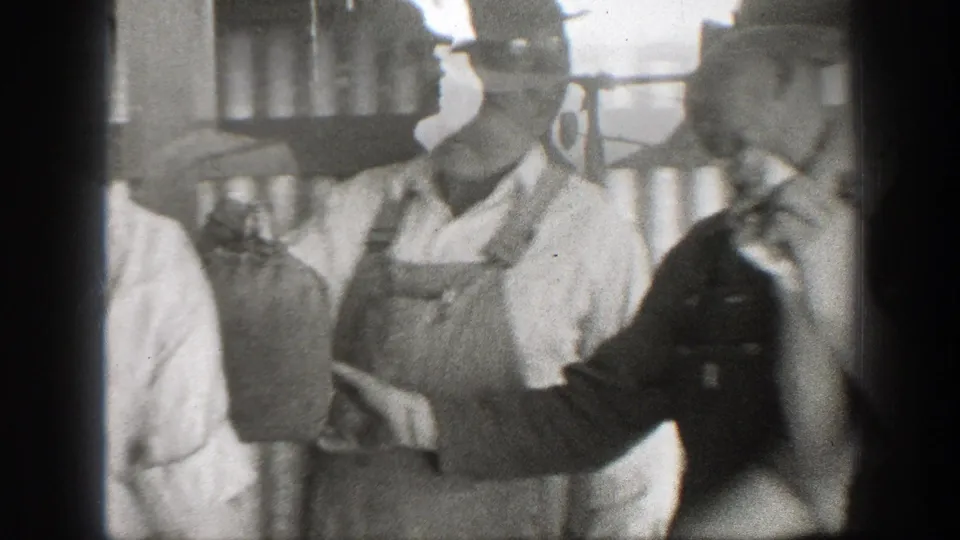 1939 California 8mm frame showing two men in hats near stacked sacks, one looking toward the camera.