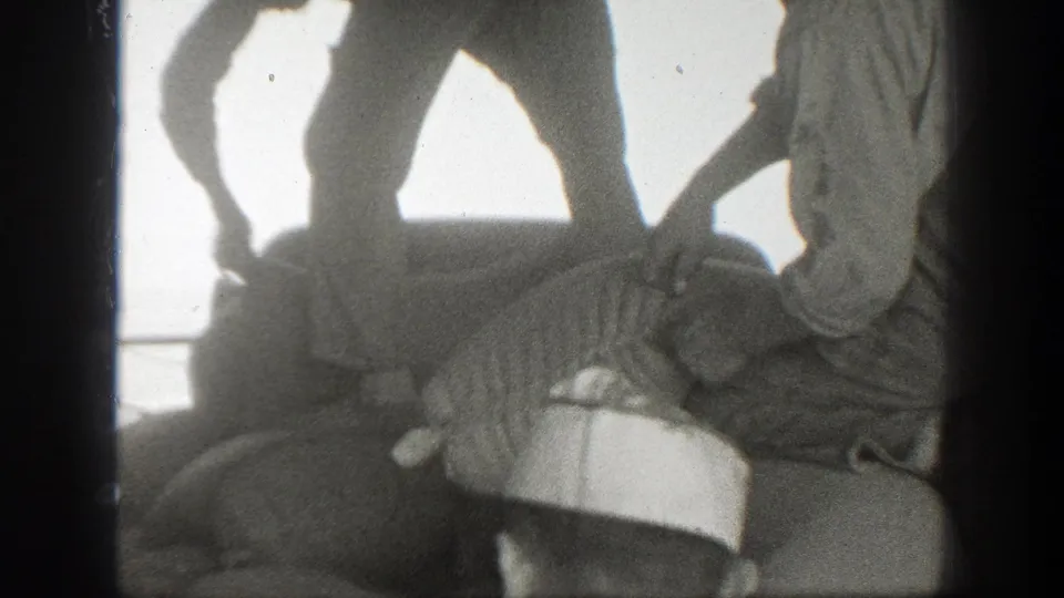 1939 California home-movie frame showing workers arranging a large sack on a pile under strong daylight.