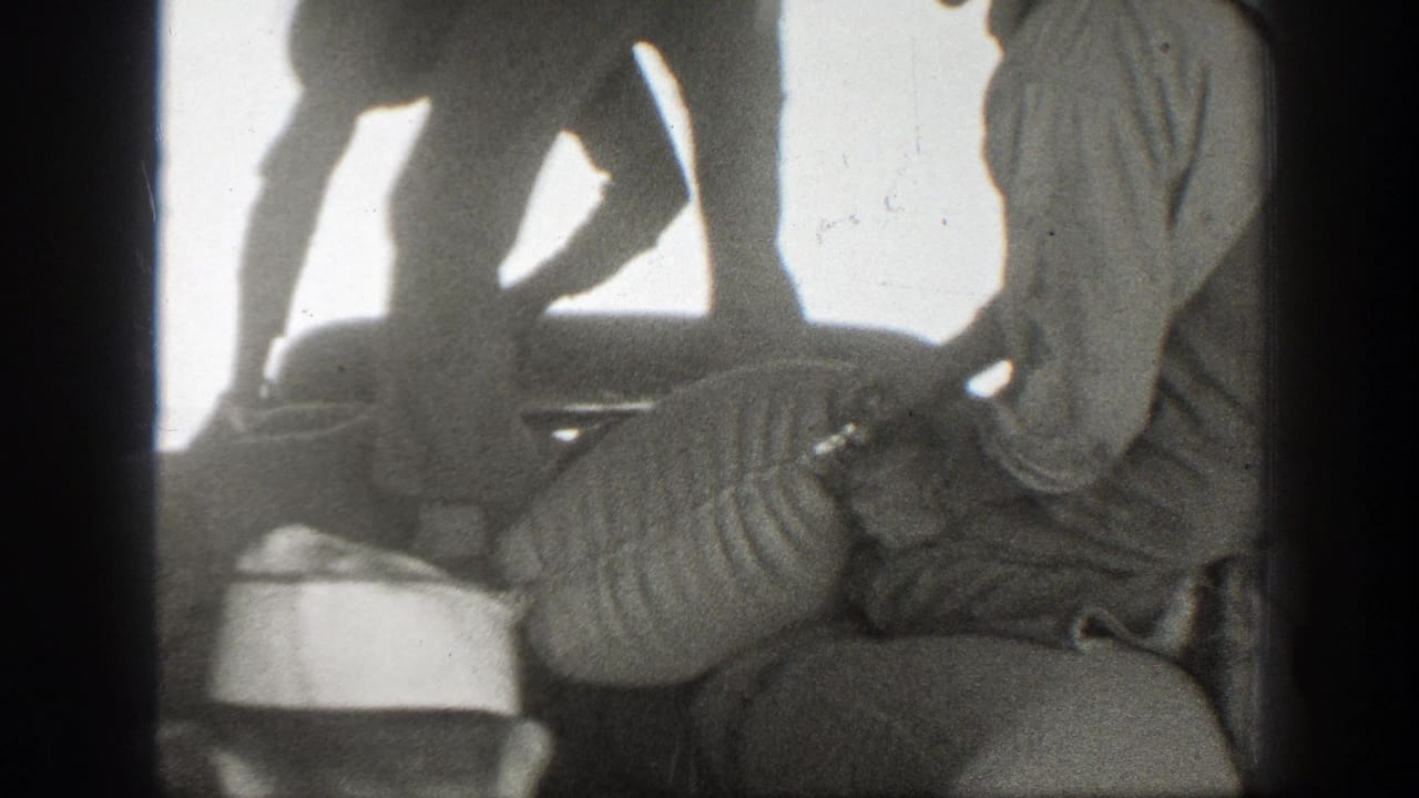 Men bend over a large sack while one works near its opening.