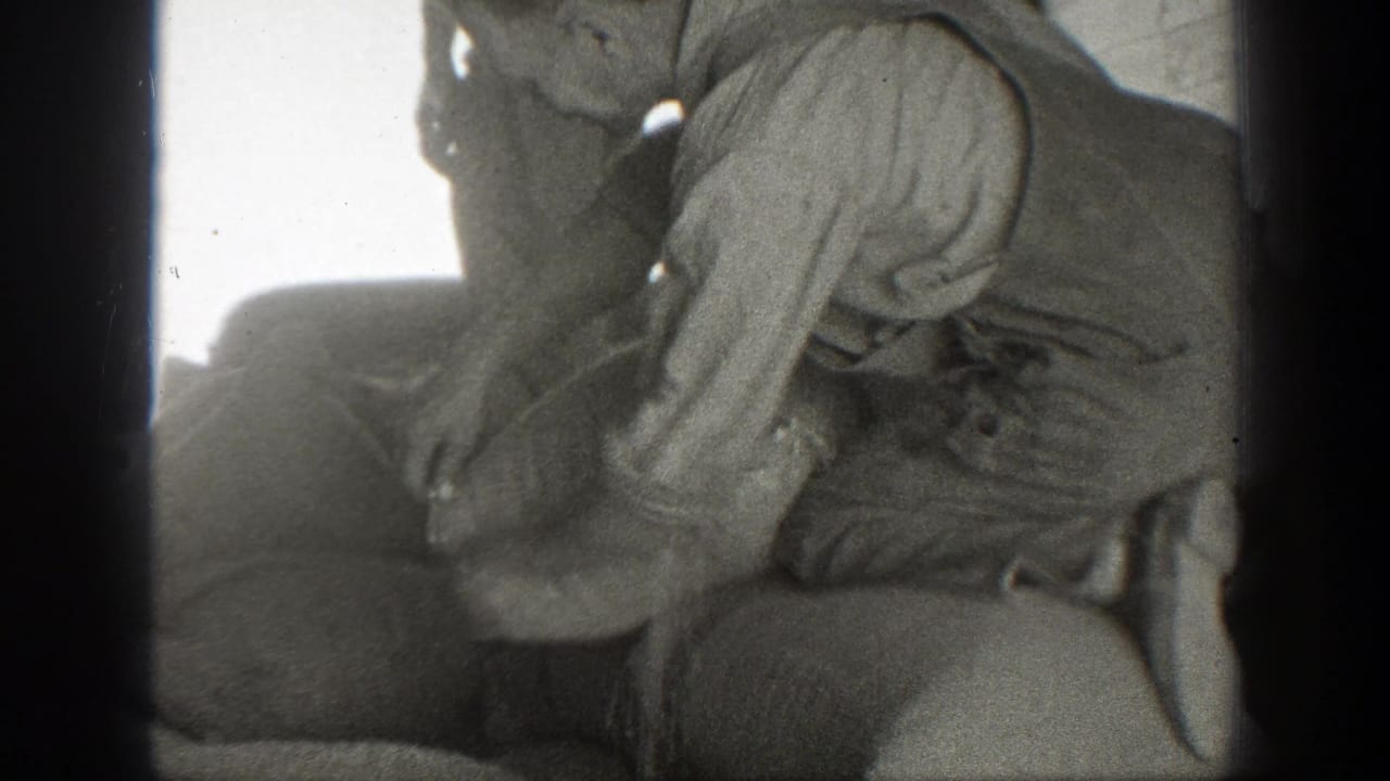 A man leans over a filled sack while another figure stands nearby.