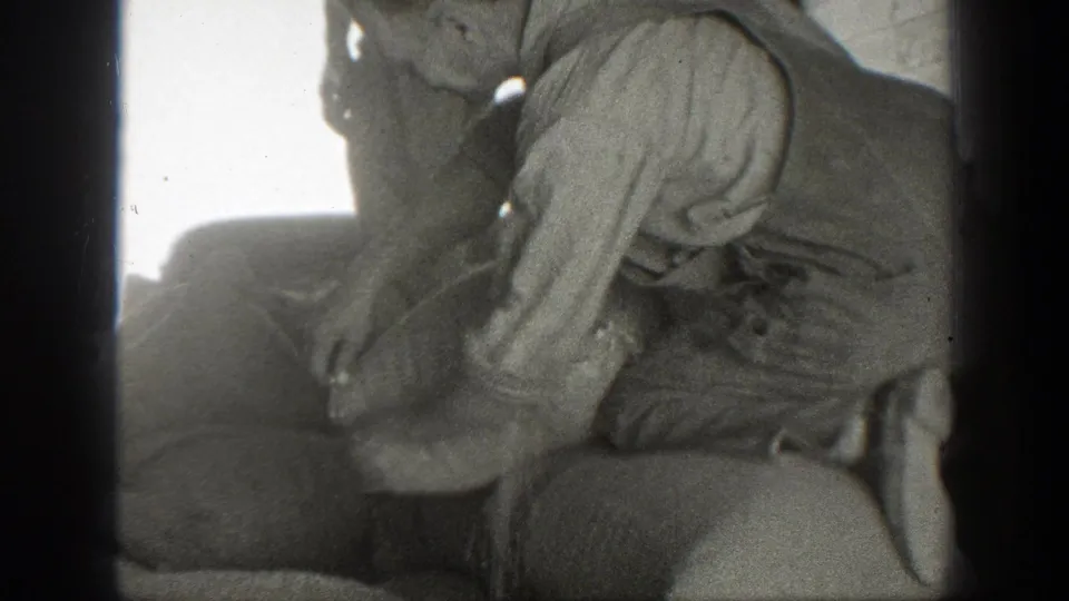 A close 1939 California frame shows a worker bent over a heaped sack, with another man partly visible at the edge.