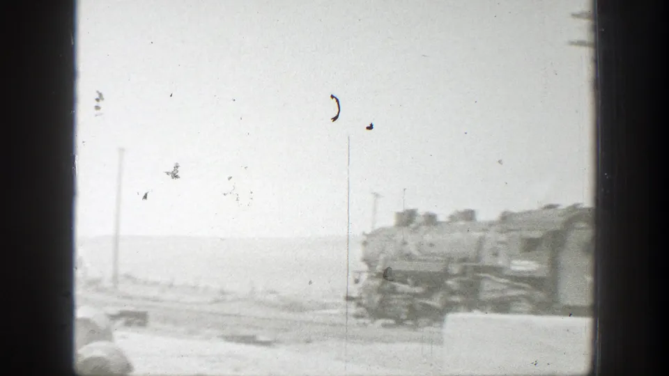 1939 California rail-yard view framed by a dark window edge, with tracks, utility poles, and distant train equipment visible.