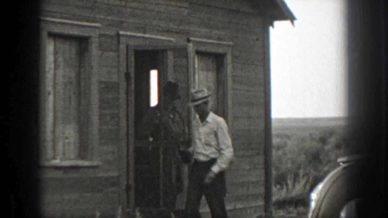 In 1939 California home-movie footage, adult men in hats and shirts gather at the doorway of a rustic wooden building.