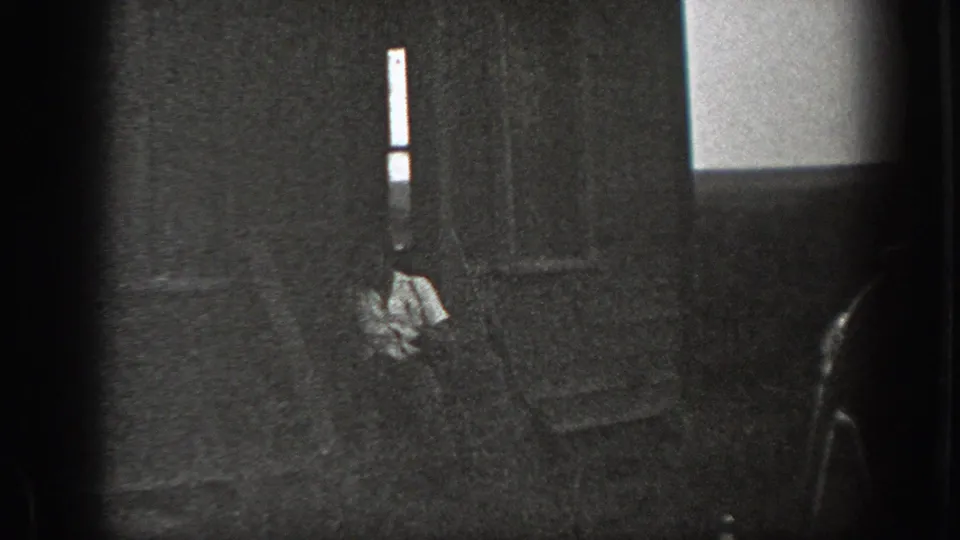 1939 California home-movie frame with a seated man in a light shirt on house steps, seen through dark foreground framing.