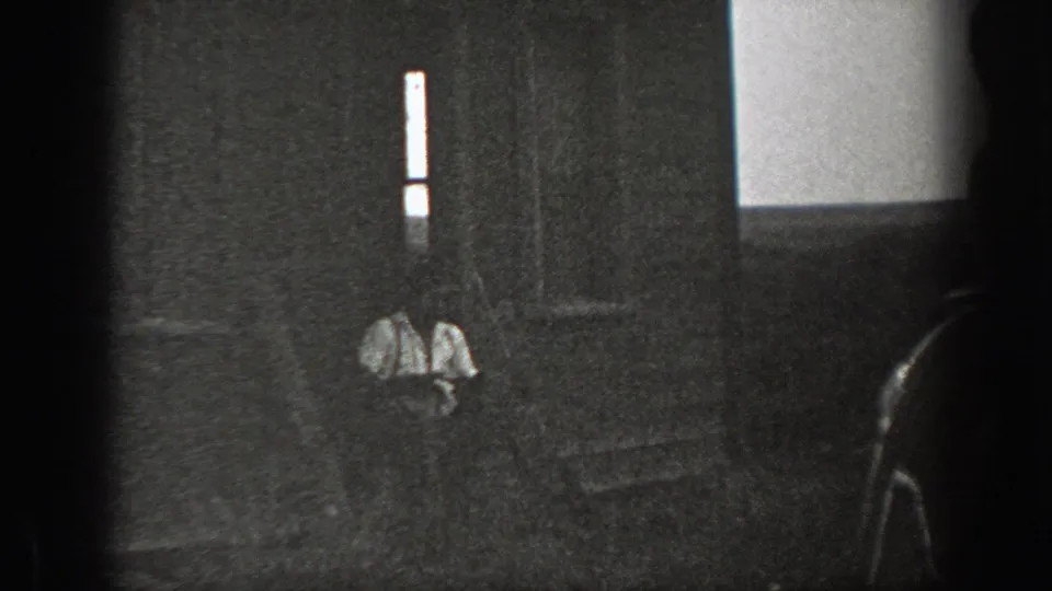 Grainy black-and-white 8mm frame from California, 1939, showing men seated near a step or doorway in deep shadow.