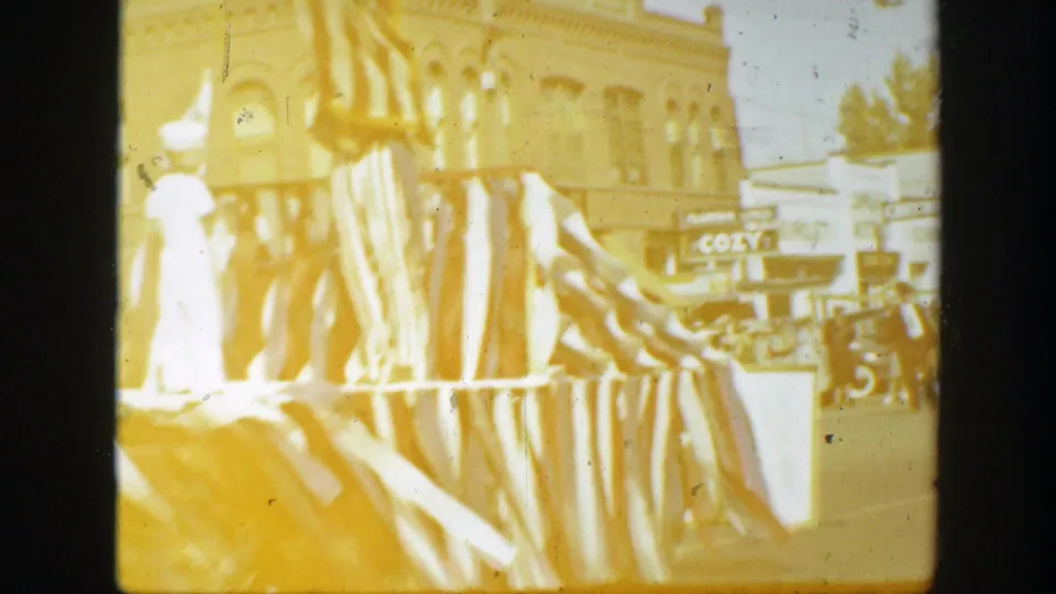 Decorated float or street display in a 1939 California scene, with draped material, pedestrians, and commercial buildings behind it.