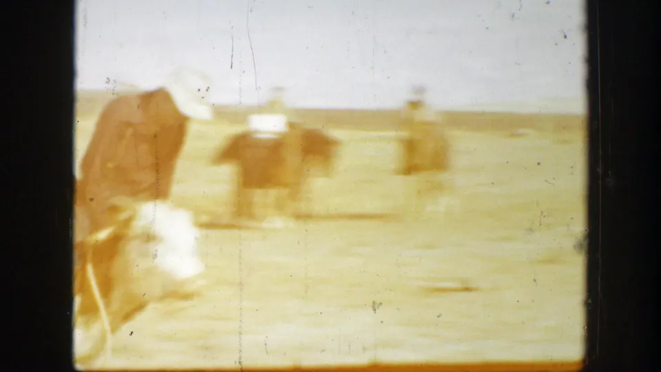 1939 California rodeo frame with a cowboy in a white hat near the bull as the action continues across the dirt arena.