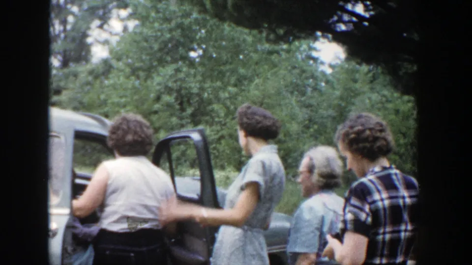 Several women stand beside an open car door in a 1953 Wisconsin home-movie farewell scene.