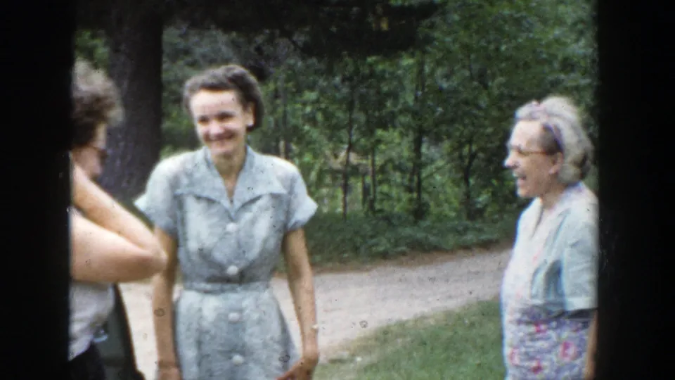 A woman in a pale dress smiles toward the camera during a 1953 Wisconsin outdoor home-movie moment.