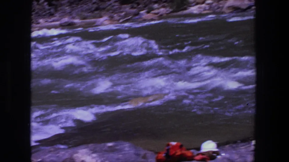 1969 Utah 8mm frame focused on churning river water, with partial bags and a white hat at the lower edge.