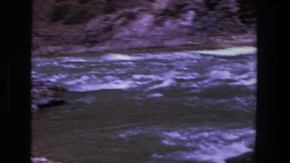1969 Utah home-movie frame showing rushing river water and a rocky bank, with the group mostly outside the frame.