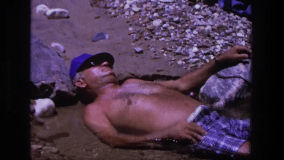 The 1969 Utah frame shows a man lying still on a rocky shoreline, with film grain and strong color shift visible.
