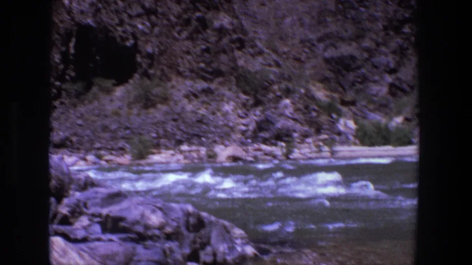 The 1969 Utah footage shows fast water, rocks, scrub, and a dark opening in the canyon wall with no clear people in this frame.