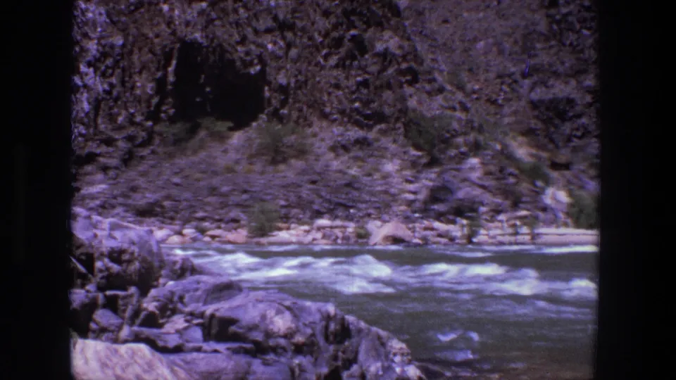 A steady 8mm view of Utah river rapids shows whitewater, rocks, and canyon terrain in bright sun.