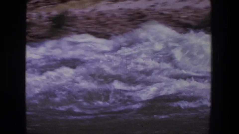 Close 1969 Utah 8mm view of churning white water, with the rocky riverbank blurred in the background.